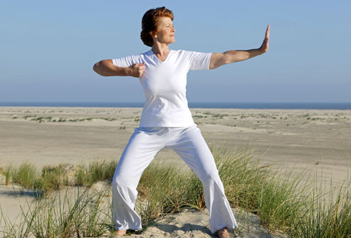 woman doing tai chi on beach